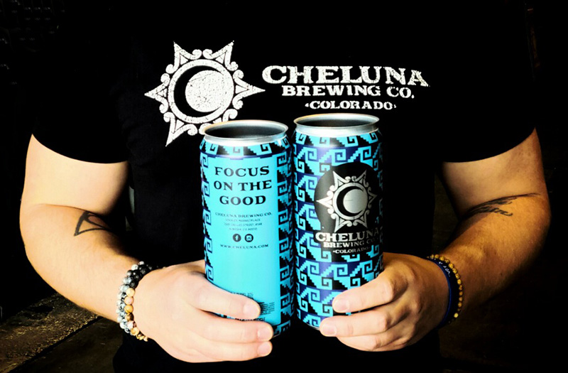 Cheluna employee in a Cheluna t-shirt showing the front and back of a Cheluna beverage can.